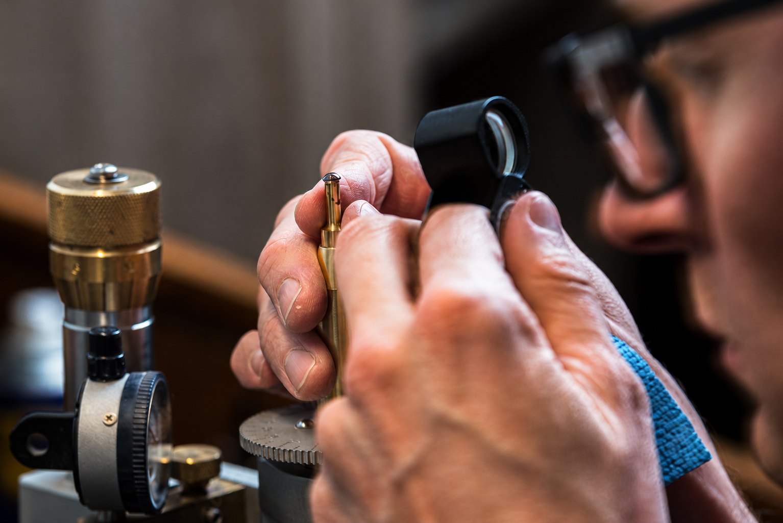 A cutter examining a stone through a loupe, dopped on a jamb peg